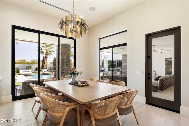 dining space with ceiling fan with notable chandelier, light hardwood / wood-style floors, and a healthy amount of sunlight