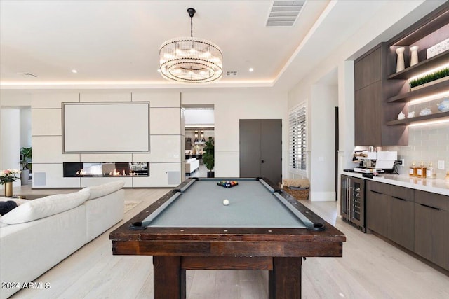 game room with beverage cooler, light wood-type flooring, a raised ceiling, and pool table