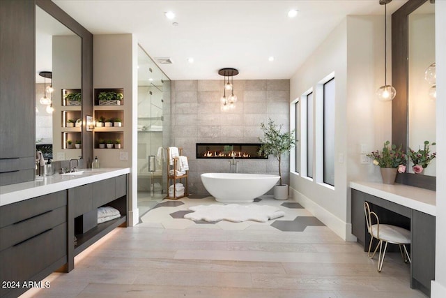 bathroom featuring wood-type flooring, vanity, plus walk in shower, and a fireplace