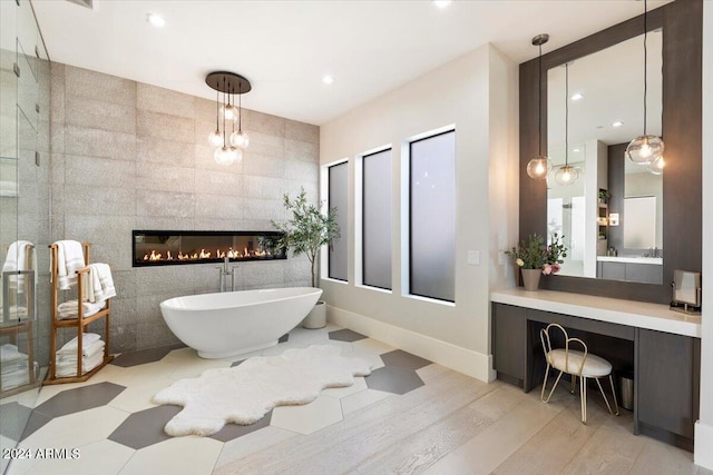 bathroom featuring separate shower and tub, vanity, hardwood / wood-style flooring, tile walls, and a tile fireplace