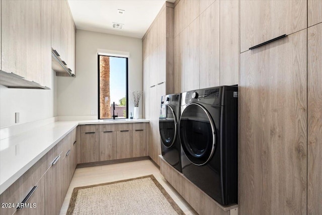 laundry room with washer and clothes dryer, sink, light tile patterned floors, and cabinets