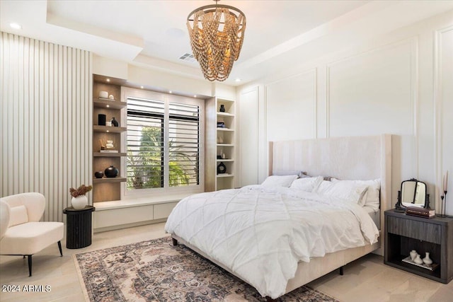 bedroom featuring a raised ceiling, a chandelier, and light hardwood / wood-style flooring