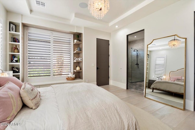 bedroom featuring a notable chandelier, light hardwood / wood-style flooring, and a raised ceiling