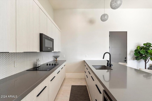 kitchen featuring black appliances, sink, light tile patterned flooring, pendant lighting, and backsplash