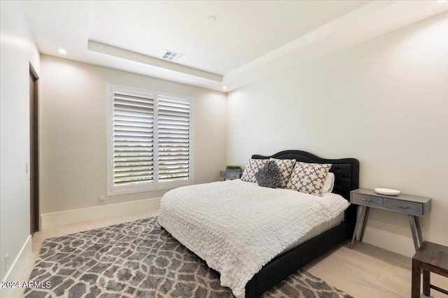 bedroom featuring a raised ceiling and light hardwood / wood-style floors