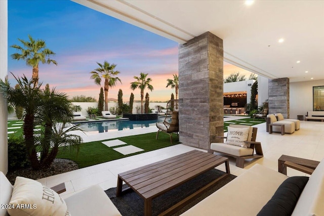 patio terrace at dusk featuring an outdoor living space and a yard