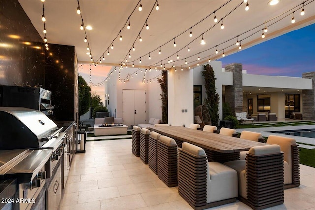 patio terrace at dusk featuring an outdoor kitchen