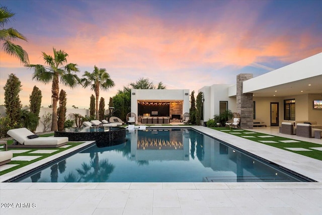 pool at dusk with a patio area