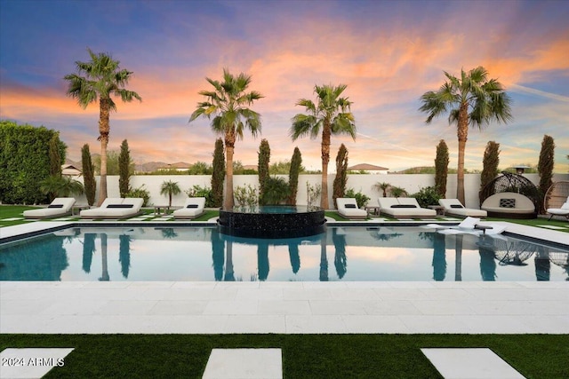 pool at dusk with a water view and a patio area