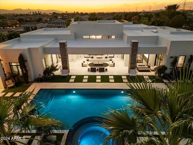 pool at dusk with an outdoor hangout area, an in ground hot tub, and a patio