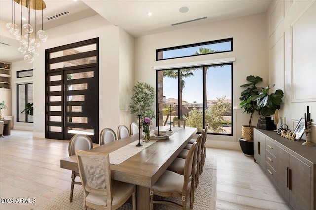 dining area with an inviting chandelier, light hardwood / wood-style flooring, and a towering ceiling