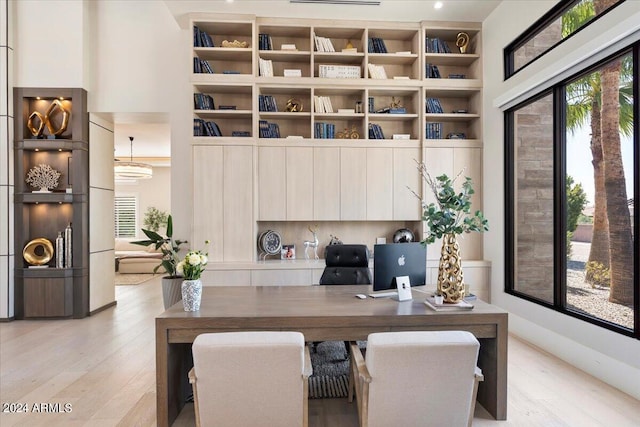 office featuring built in shelves and light hardwood / wood-style flooring