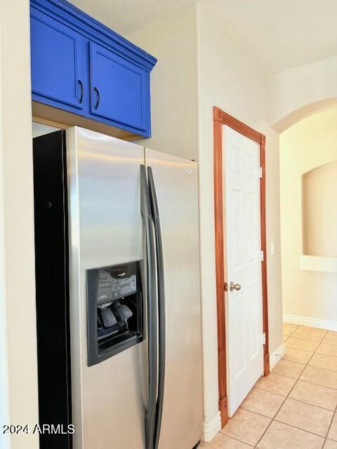 kitchen with blue cabinets, stainless steel fridge with ice dispenser, and light tile patterned floors