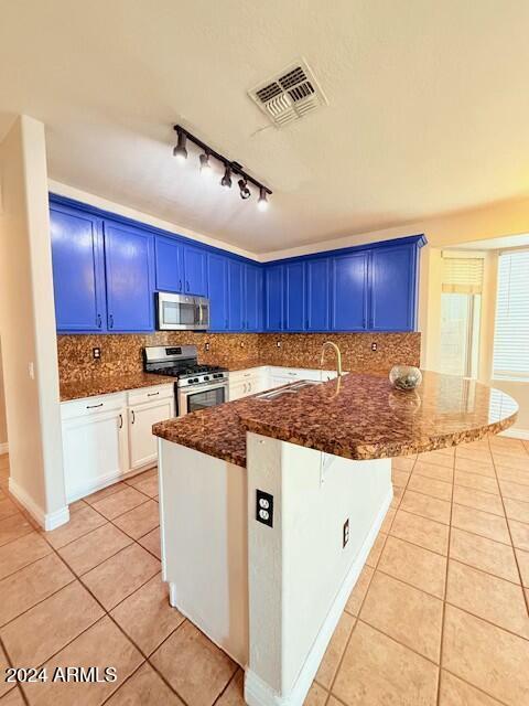 kitchen featuring blue cabinets, a breakfast bar, light tile patterned floors, kitchen peninsula, and stainless steel appliances