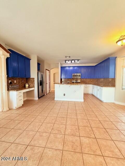 kitchen featuring blue cabinets, a breakfast bar, light tile patterned floors, appliances with stainless steel finishes, and decorative backsplash