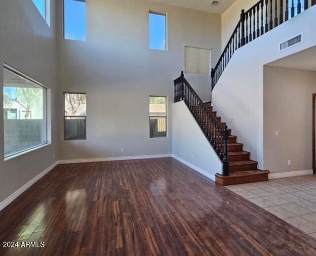 unfurnished living room featuring hardwood / wood-style flooring and a towering ceiling