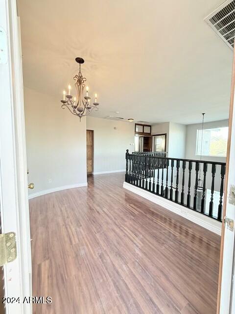 spare room featuring wood-type flooring and an inviting chandelier