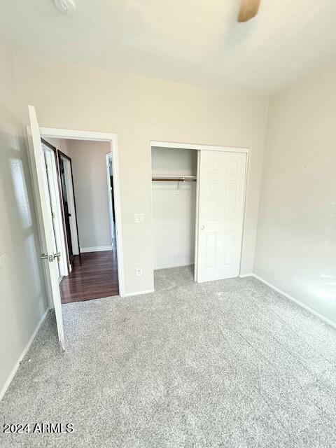 unfurnished bedroom with ceiling fan, a closet, and carpet