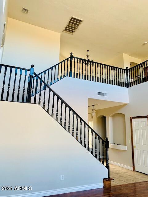 stairs with a towering ceiling and hardwood / wood-style flooring