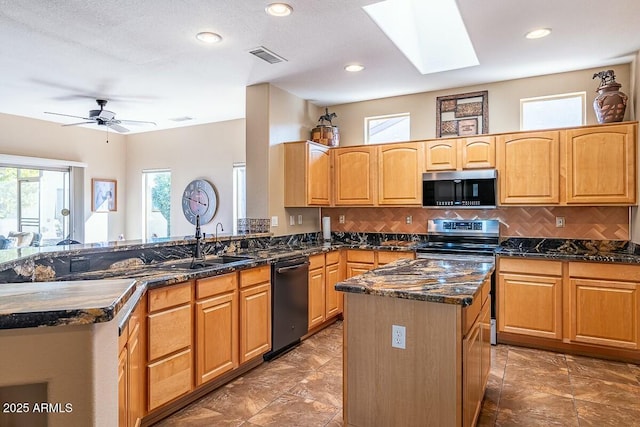 kitchen with appliances with stainless steel finishes, a center island, a skylight, decorative backsplash, and kitchen peninsula