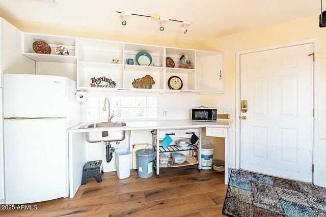 kitchen with wood-type flooring, white refrigerator, and sink