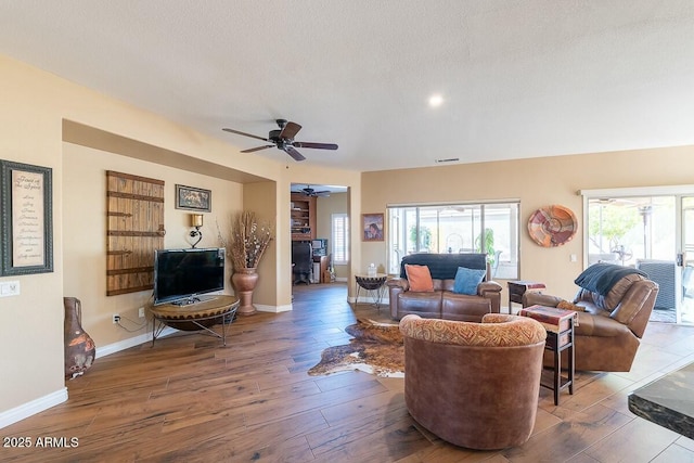 living room featuring hardwood / wood-style flooring, ceiling fan, and a textured ceiling