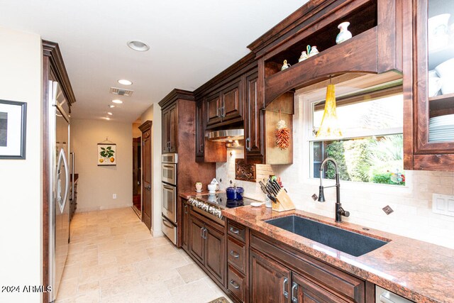 kitchen featuring light stone counters, sink, stainless steel appliances, and tasteful backsplash