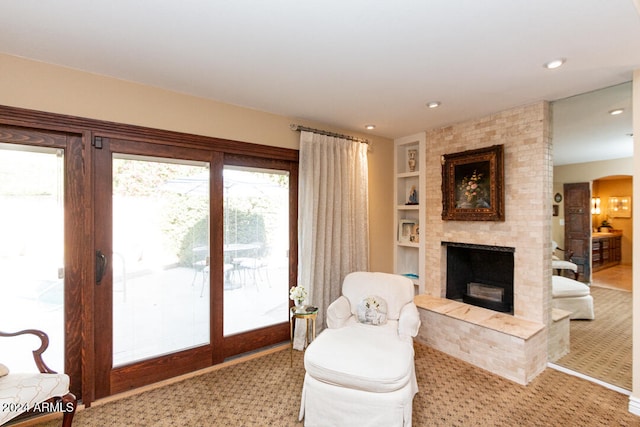 carpeted living room with built in shelves and a large fireplace