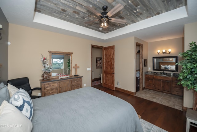 bedroom with ceiling fan, a sink, baseboards, light wood-type flooring, and a tray ceiling