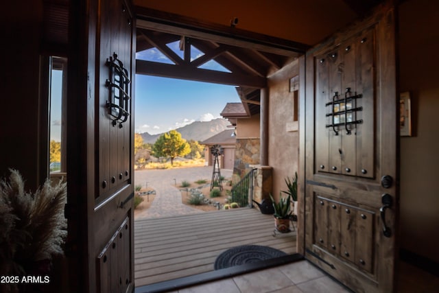 doorway with lofted ceiling, light tile patterned floors, and a mountain view