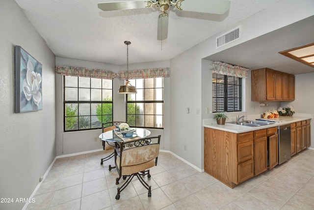 kitchen featuring hanging light fixtures, sink, dishwasher, light tile patterned floors, and a textured ceiling