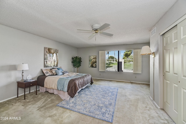 carpeted bedroom with ceiling fan, a textured ceiling, and a closet