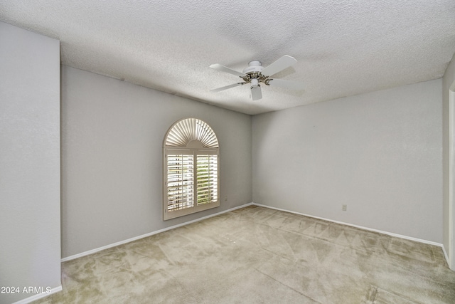 spare room featuring a textured ceiling, light colored carpet, and ceiling fan