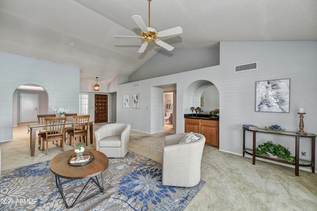 carpeted living room with ceiling fan, a textured ceiling, and lofted ceiling