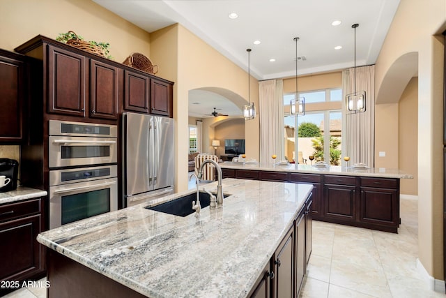 12904 W Dale Ln, Peoria, AZ 85383 - kitchen featuring appliances with stainless steel finishes, arched walkways, an island with sink, light stone countertops, and recessed lighting