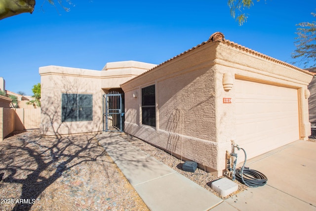 mediterranean / spanish house featuring a garage, fence, a tiled roof, and stucco siding