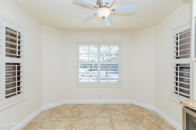 empty room with beverage cooler, baseboards, and a ceiling fan