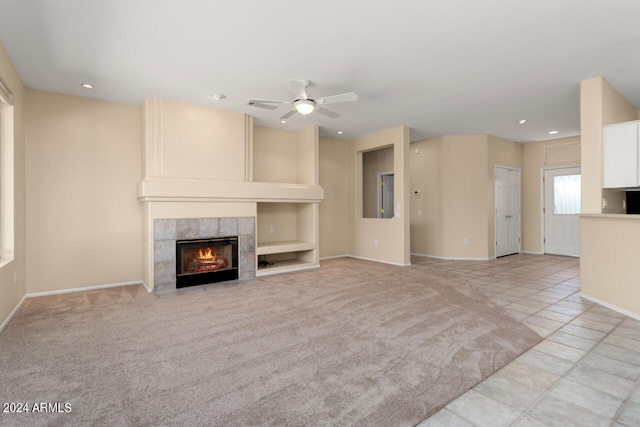 unfurnished living room featuring light colored carpet, ceiling fan, and a tile fireplace