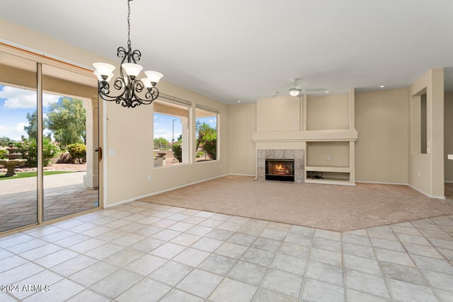 unfurnished living room featuring light tile flooring, ceiling fan with notable chandelier, and a fireplace