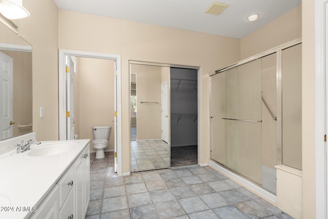 bathroom featuring oversized vanity, toilet, tile floors, and a shower with shower door