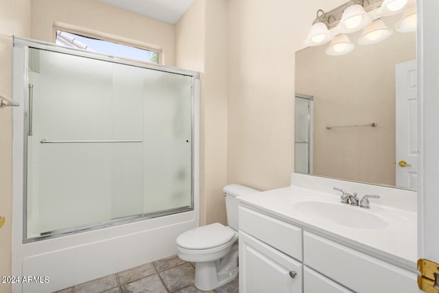 full bathroom featuring tile flooring, combined bath / shower with glass door, vanity with extensive cabinet space, and toilet