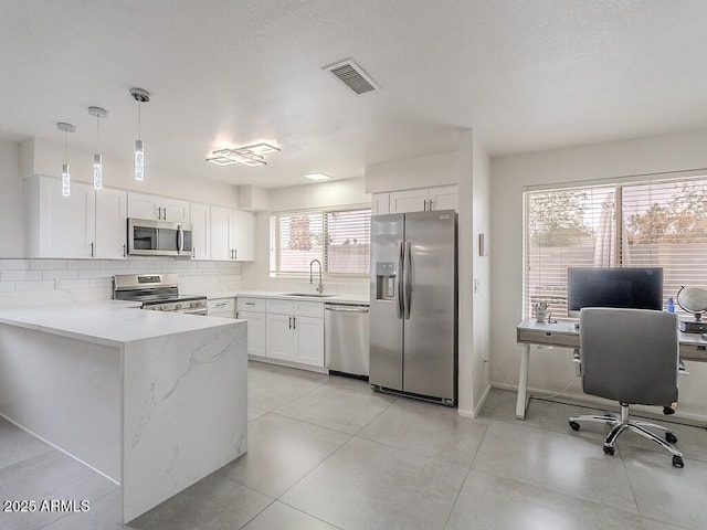 5817 S Siesta Ln, Tempe, AZ 85283 - kitchen with appliances with stainless steel finishes, a sink, white cabinets, light stone counters, and decorative backsplash