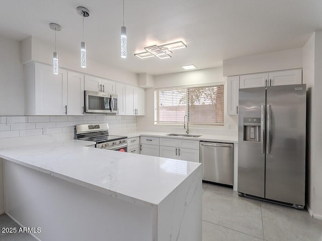 5817 S Siesta Ln, Tempe, AZ 85283 - kitchen with appliances with stainless steel finishes, a sink, a peninsula, white cabinets, and decorative backsplash