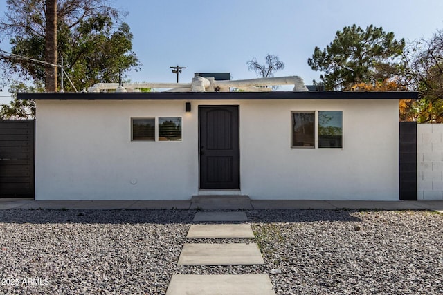 ranch-style house featuring fence and stucco siding