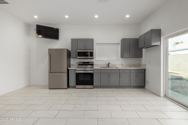 kitchen featuring appliances with stainless steel finishes, gray cabinets, light countertops, and a sink