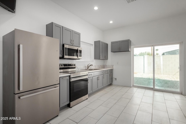 kitchen with a sink, gray cabinets, stainless steel appliances, and light countertops