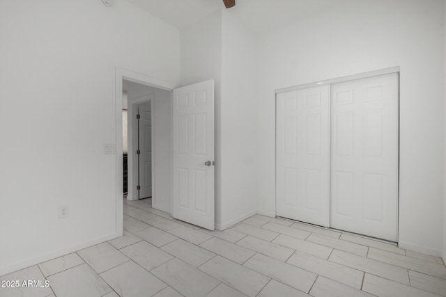 unfurnished bedroom with a closet, a towering ceiling, and baseboards