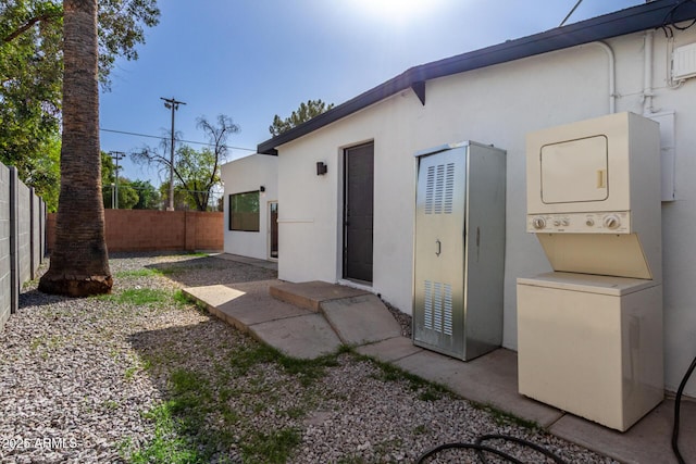 exterior space featuring stacked washer / drying machine, a patio area, fence, and stucco siding