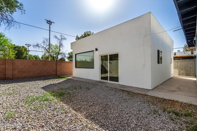 back of house featuring fence and stucco siding