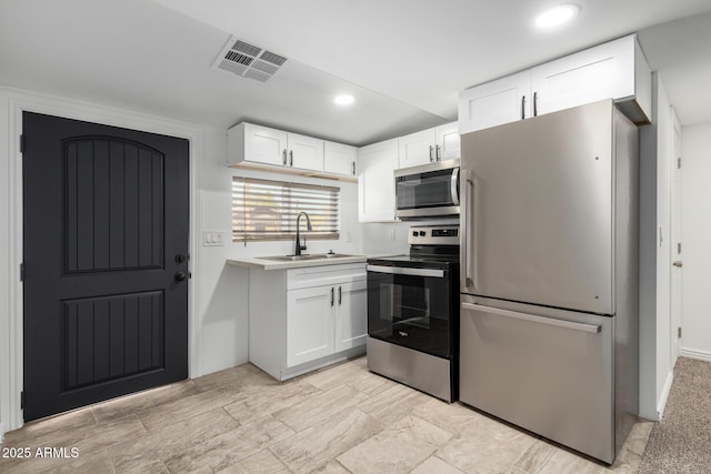 kitchen featuring stainless steel appliances, light countertops, visible vents, white cabinets, and a sink